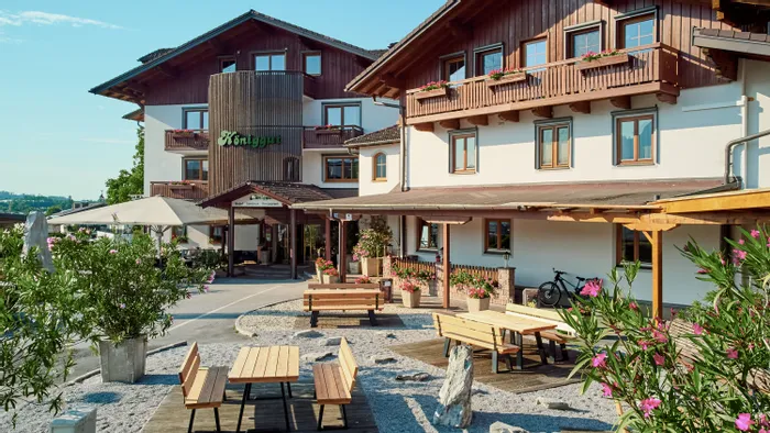 Traditionelles Alpenhotel mit Holzbalkonen, Sitzbereich im Freien und blühenden Pflanzen
